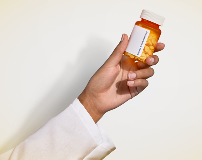 A hand holding an Express Scripts Canada Pharmacy medication pill bottle