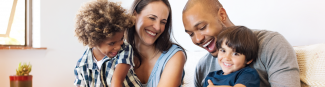 Un couple interracial et ses deux enfants rient ensemble.